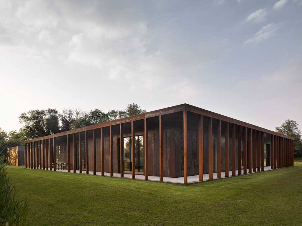 Modern building with rusted steel façade on green lawn.